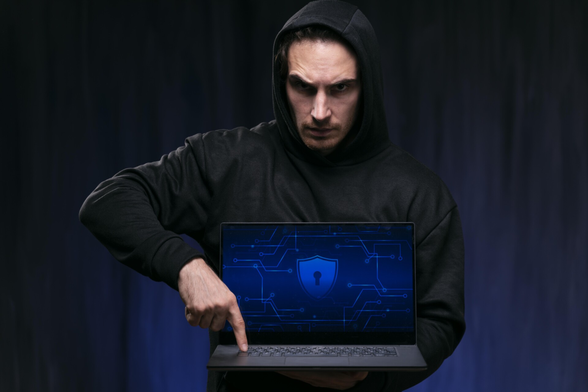 a man in a black hoodie holding a laptop